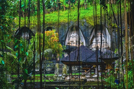 View of the ancient stone shrines at Gunung Kawi Temple, carved into the cliffs and surrounded by lush greenery, offering a peaceful and mystical atmosphere