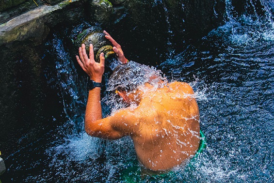 Person participating in a Melukat ritual at Tirta Empul Temple in Bali, allowing the holy water to cleanse and purify their body and soul.