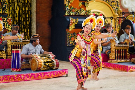 Traditional Balinese dancers performing during a vibrant cultural festival, accompanied by gamelan musicians playing traditional instruments.