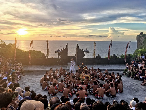 Performers in traditional costumes during the Kecak Dance at Uluwatu Temple, with a dramatic sunset backdrop over the Indian Ocean