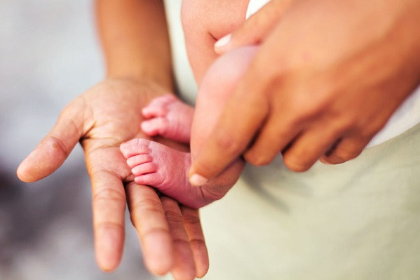 Close-up of a parent holding the tiny feet of a newborn baby.