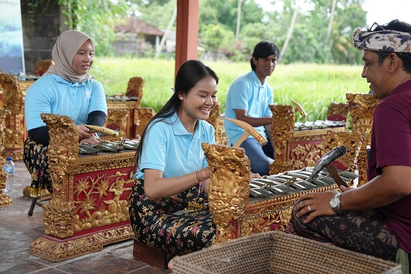 Participants enjoying a Gamelan experience, playing traditional Balinese instruments under the guidance of a local instructor in a serene outdoor setting.