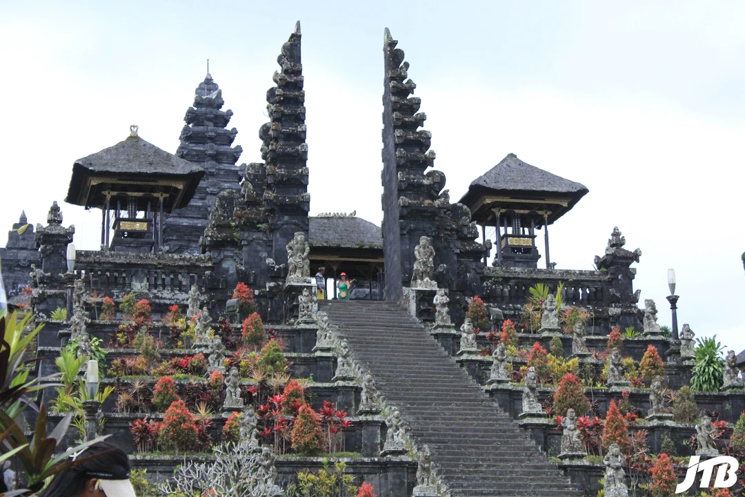 A photo of Besakih Temple, a Hindu temple complex on the slopes of Mount Agung in Bali, Indonesia.</p>
<p>This is an impressive image of Besakih Temple, which is the largest and holiest temple of Balinese Hinduism. The temple complex consists of 22 separate temples that are built on six levels, terraced up the slope of the volcano. The main temple is Pura Penataran Agung, which has a lotus throne as the symbolic center and the ritual focus of the entire complex. The temple dates back to the 15th century and has a rich history and culture. The temple hosts many festivals and ceremonies throughout the year, attracting pilgrims and visitors from all over the world.