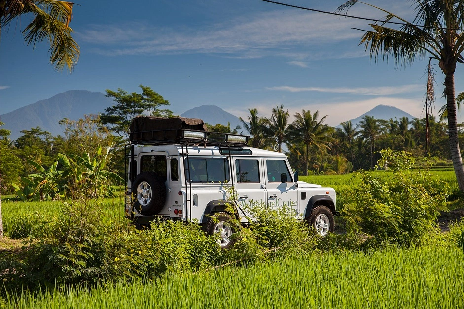 Bali rainforest adventure 4WD vehicle passing green rice fields and mountain scenery